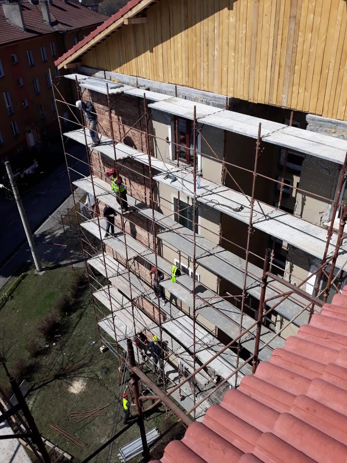 Lucru la fațadă de pe schelă, văzut de la nivelul acoperișului
