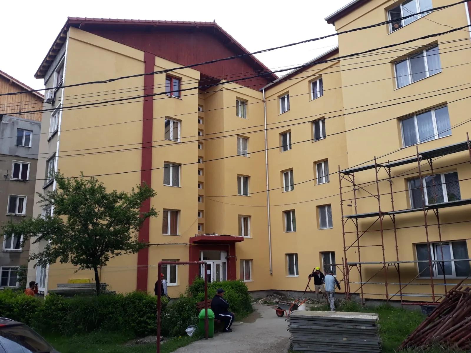 Bloc cu fațada finisată în galben și brâuri cărămizii, cu ultimele schele
