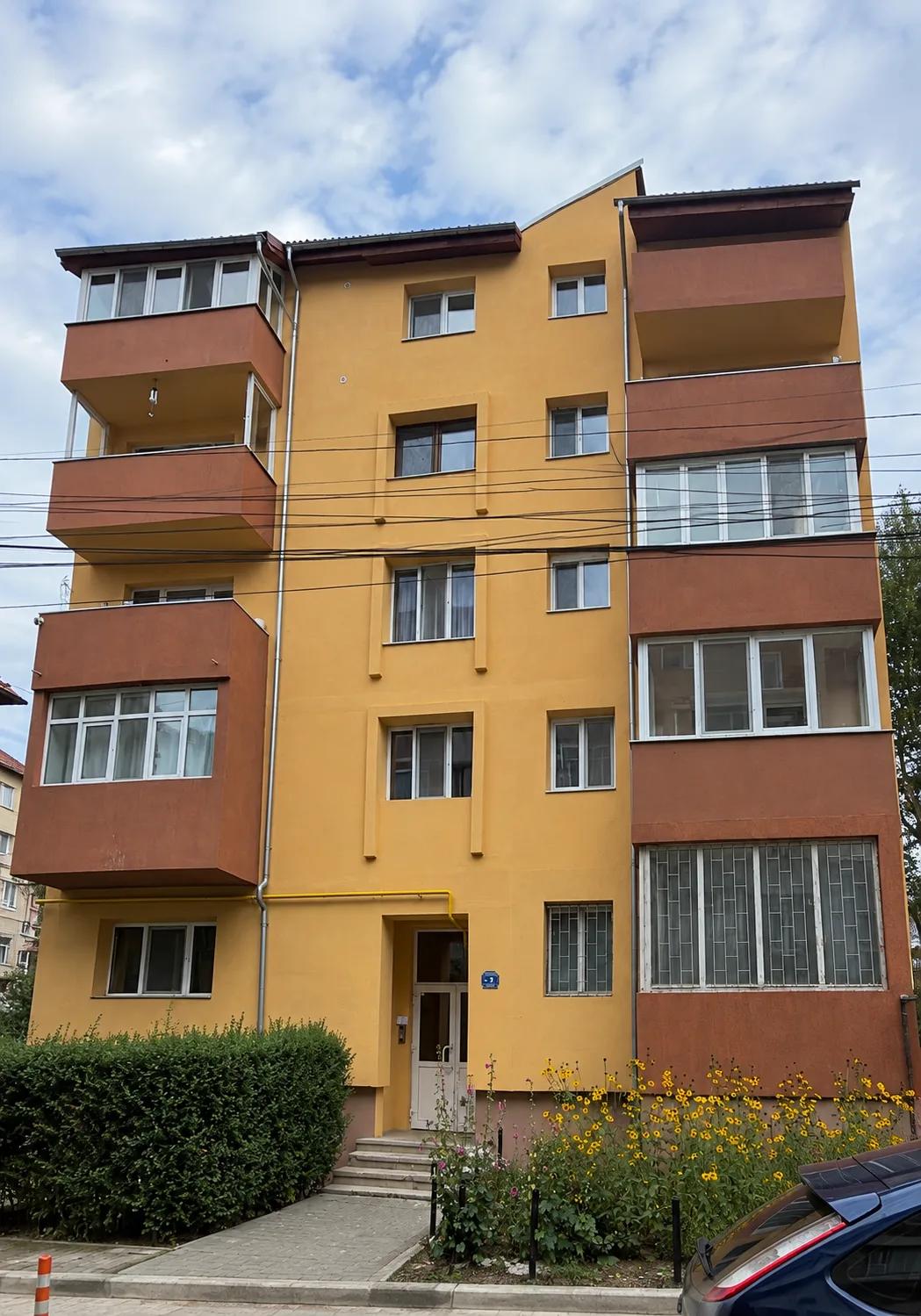 Fațada principală a blocului după termoizolare, finisată în galben și cărămiziu